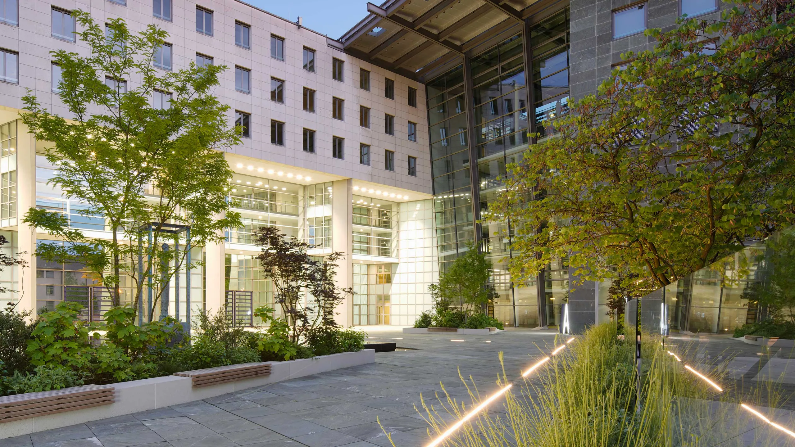 Außenaufnahme GRIDD mit begrüntem Innenhof bei Dämmerung mit Blick auf Gebäudeteil A